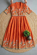 Orange embroidered dress on a woven mat with a plant