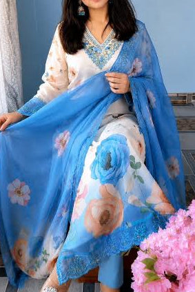 Woman holding a blue floral scarf in a room with pink flowers and a blue wall.