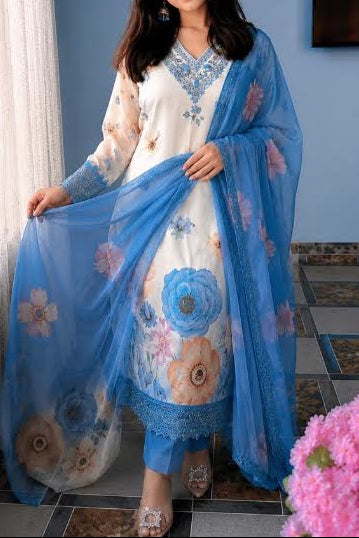Woman holding a blue embroidered dupatta in a room with a television and curtains.