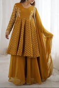 Woman wearing a mustard yellow traditional outfit with white patterns against a white curtain background