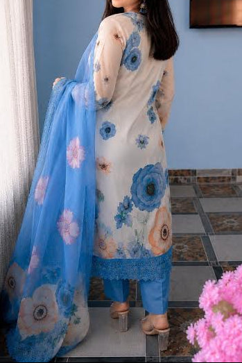 Woman in a floral dress with a blue dupatta standing indoors.